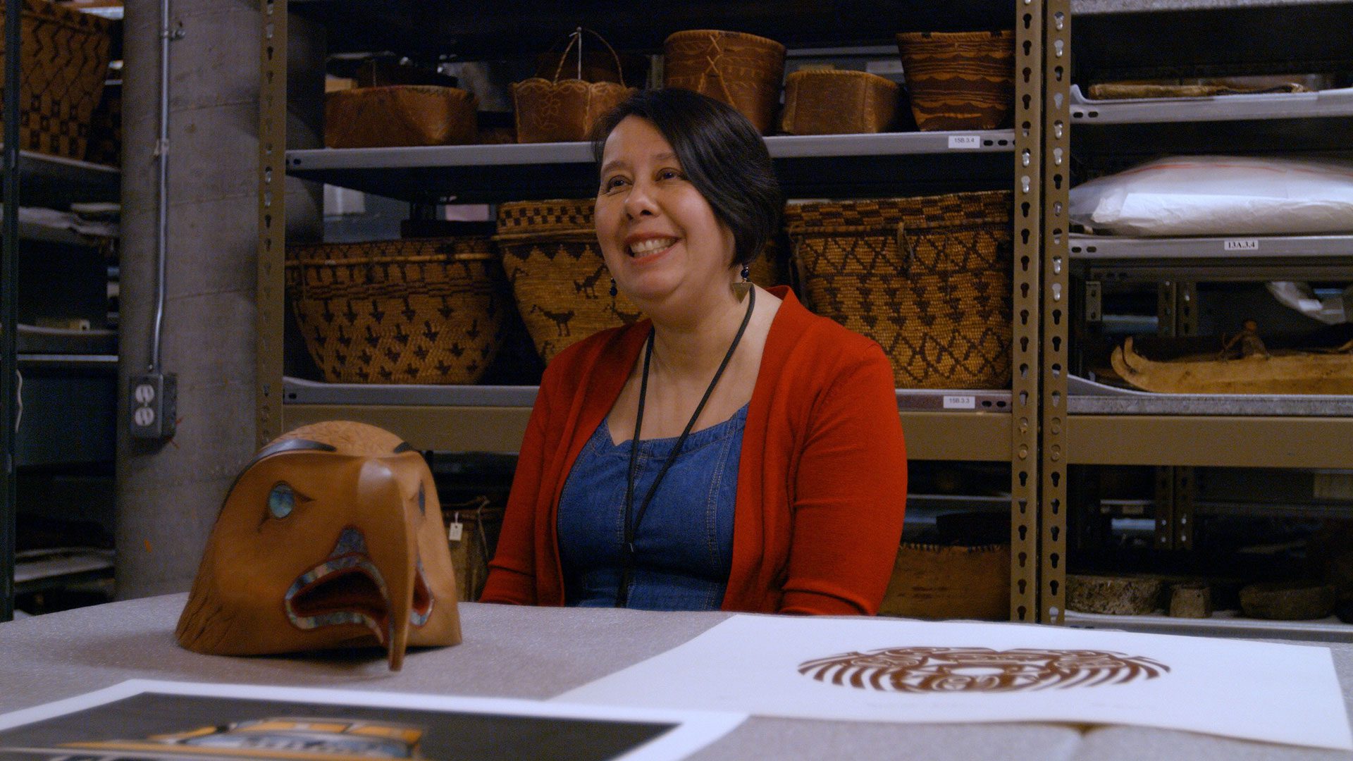 Sharon Fortney curator at the Museum of Vancouver talks about reconciliation in front of a Norman Tait Mask